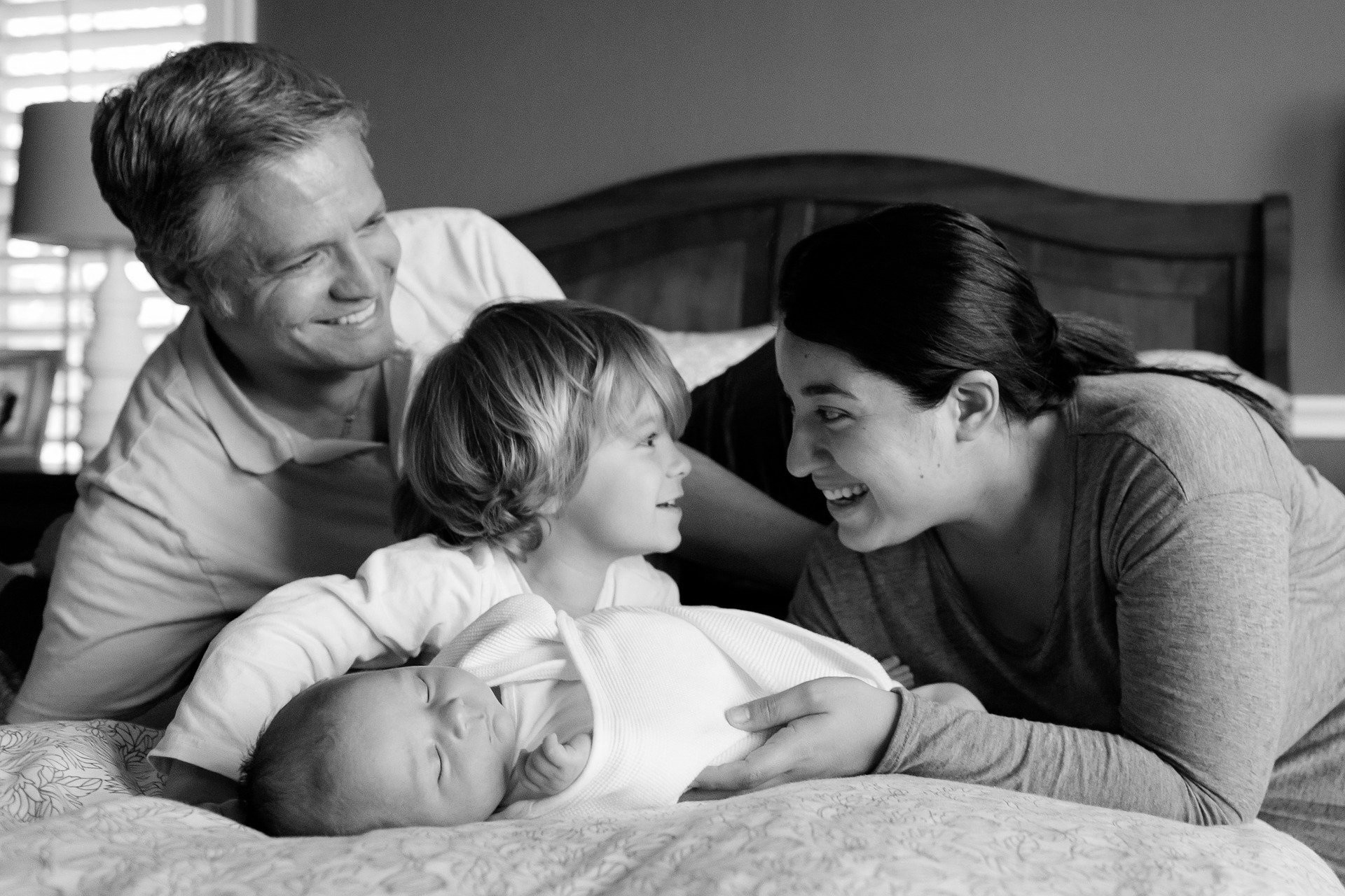 Family of four lying on a bed in black and white