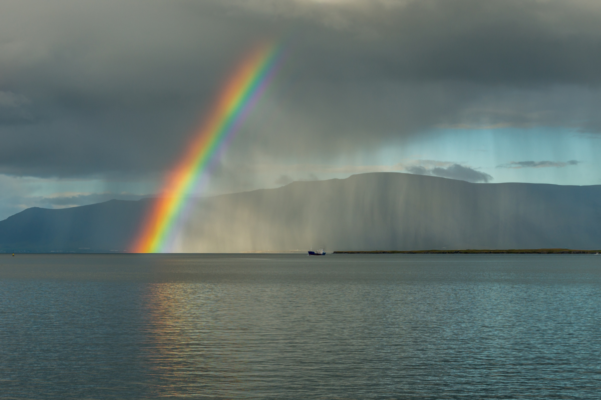 Rainbow and rain over a calm sea