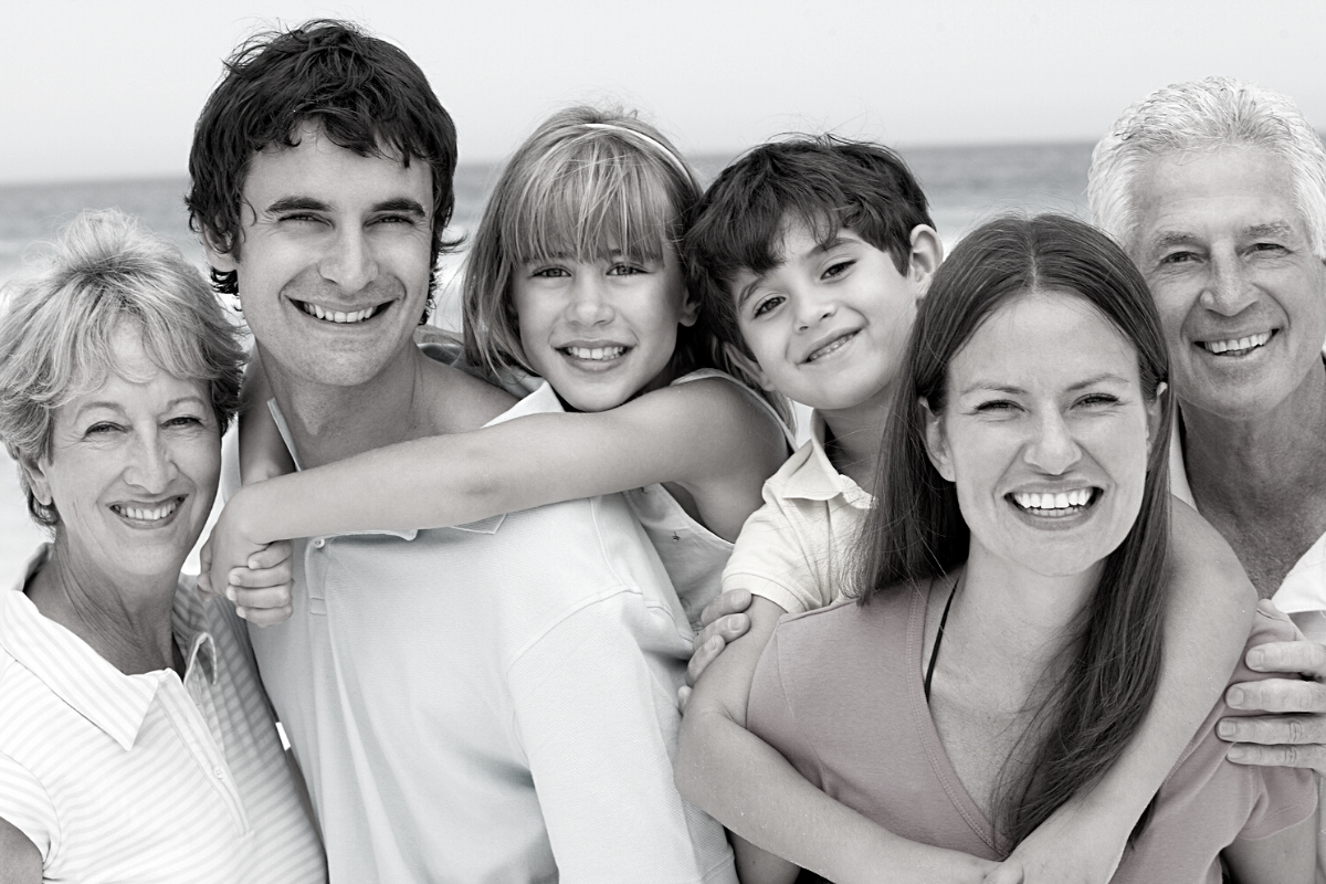 Black and white picture showing three generations of a family happy on a beach