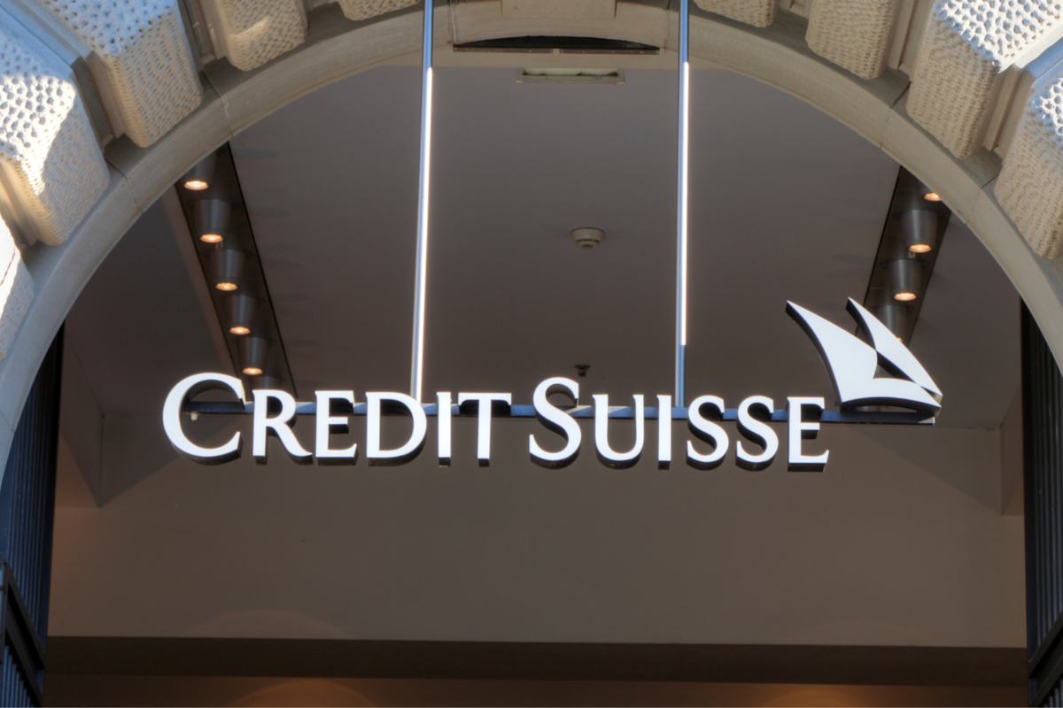 Credit Suisse sign in white hanging from an white brick arch at an entrance to a building