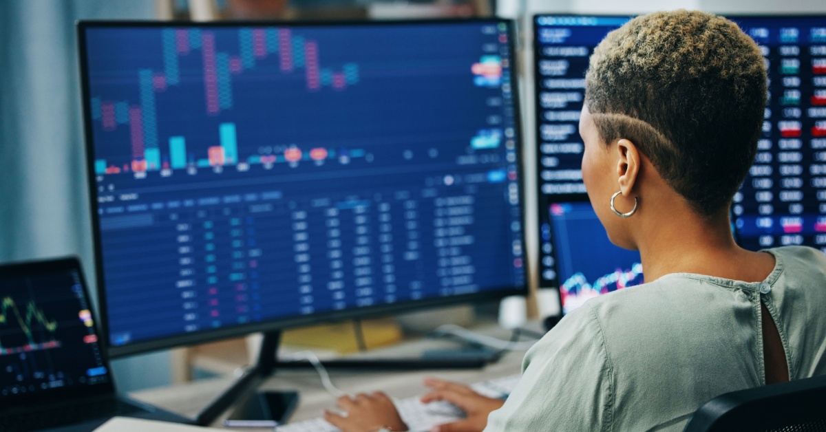 A woman looking at stock market data on a computer screen