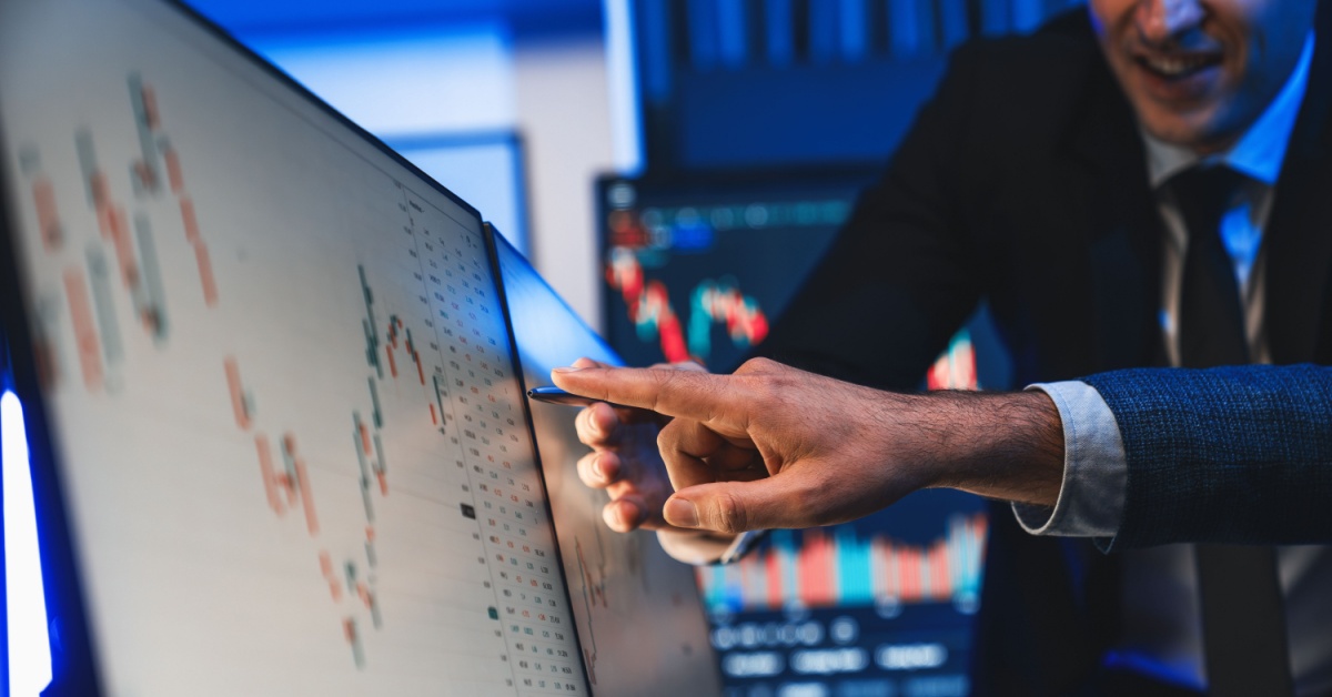 Two traders looking and pointing at an index on a computer screen