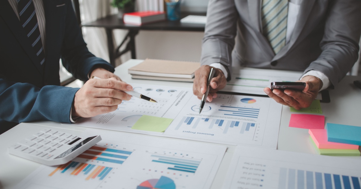 A working meeting with investment charts spread on the table.