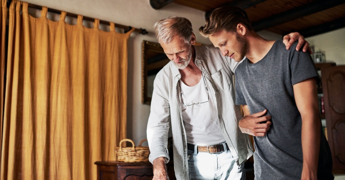 A dad with his arm around his son as they look at a business plan.