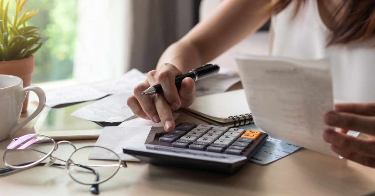 A woman holding a bill and a calculator.