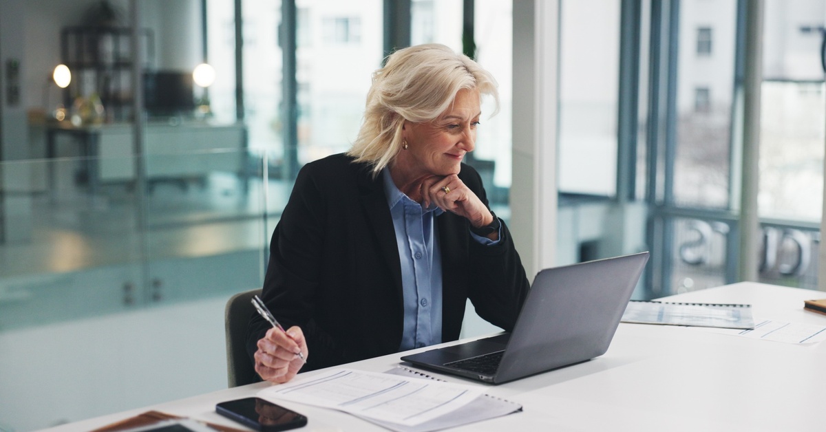 An older businesswoman sitting at a computer